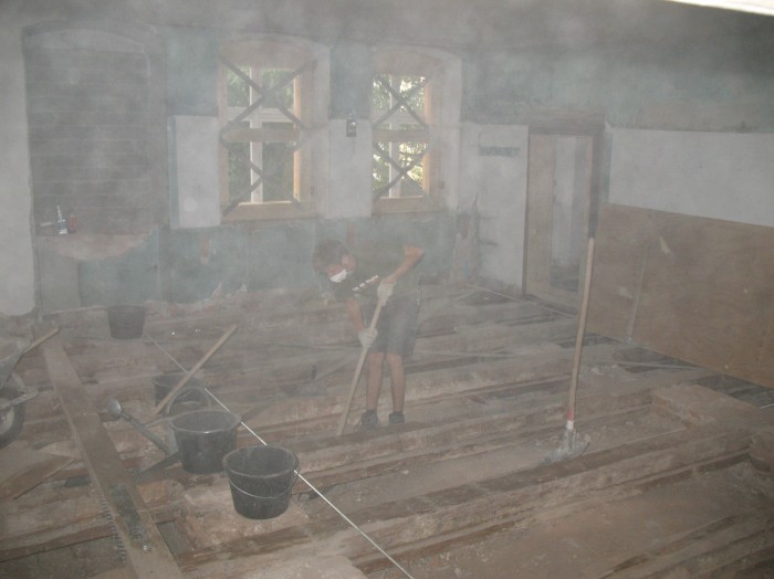Ein Arbeiter räumt die Fehlböden des alten Museumsgebäudes aus, der ganze Raum ist voller Staub