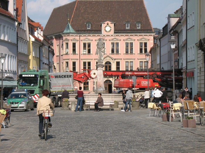 Blick von der Kaiser-Max-Straße Richtung Rathaus, ein Polizeiwagen gefolgt von mehreren Baustellenfahrzeugen von der Sedanstraße in die Kaiser-Max-Straße einbiegend