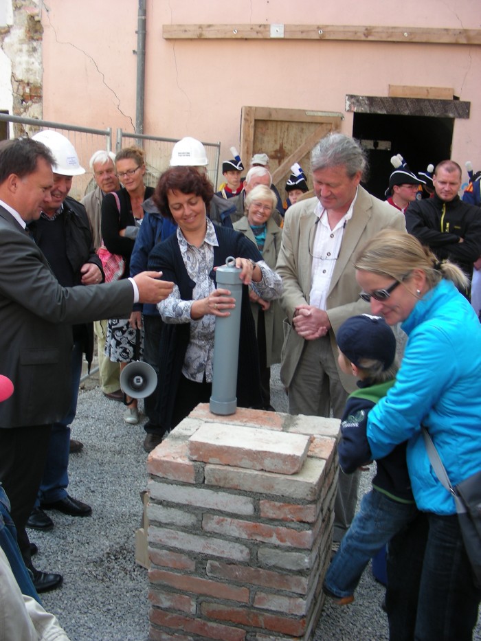 Links Herr OB Stefan Bosse, rechts daneben Frau Dr. Astrid Pellenghar, welche eine Röhre zuschraubt, daneben der Bauleiter, im Hintergrund Zuschauer und Mitglieder der Knabenkapelle bei der Grundsteinlegung