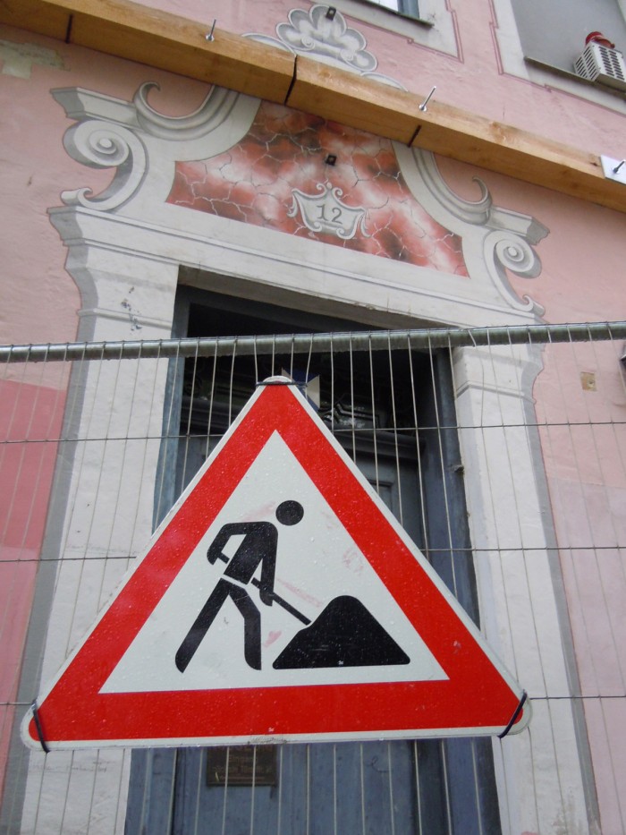 Fassade des alten Museums mit einer Türe, davor ein Bauzaun mit einem Baustelle-Schild