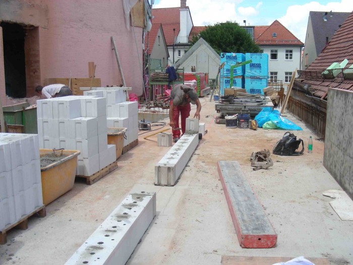 Blick auf den Rohbau des 2. Obergeschoßes, es stehen verschiedene Baumaterialien auf dem Boden, ein Bauarbeiter mauert eine Wand für den zukünftigen Museumspädagogikraum