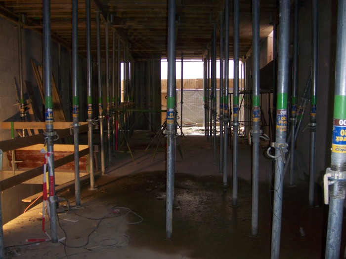 Blick durch das im Bau befindliche Foyer auf den zukünftigen Eingang, im ganzen Raum stehen Metallstützen, auf der linken Seite ist der Abgang zum Untergeschoss zu erkennen.