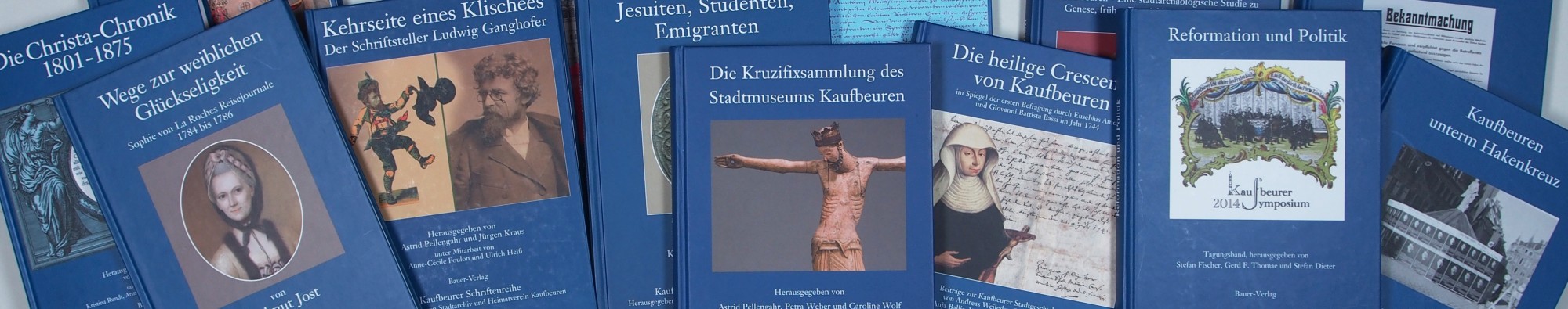 Kaufbeurer Schriftenreihe: mehrere dunkelblaue Bücher liegen sich teilweise überschneidend nebeneinander