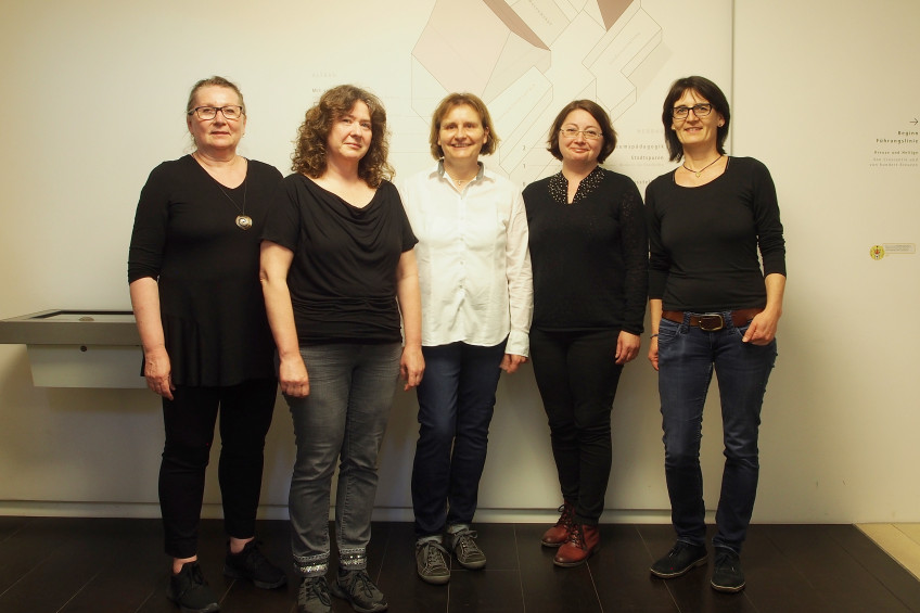 Fünf Mitarbeiterinnen des Kassen- und Aufsichtsteams nebeneinander stehend, in schwarz bzw. in schwarz/weiß gekleidet