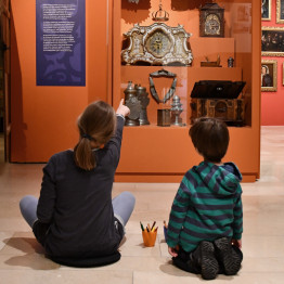 zwei Kinder sitzen vor einer Vitrine in der Sonderausstellung