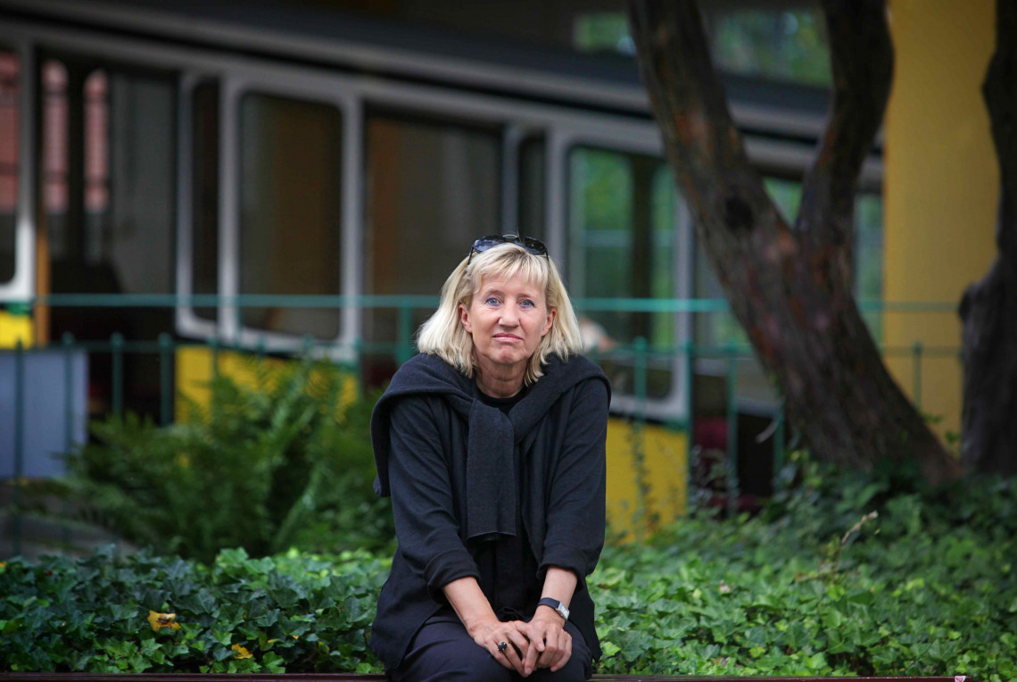 Schriftstellerin Ines Geipel sitzend vor einer Hecke und einem Baum, im Hintergrund verschwommen eine Gondel