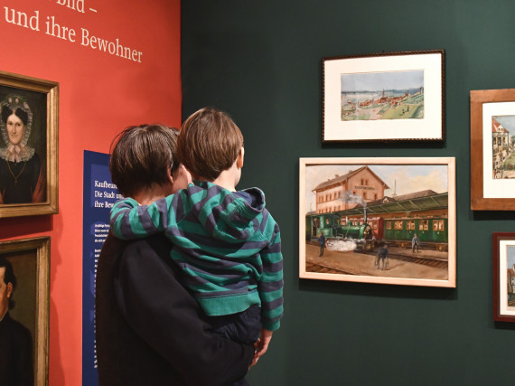 Ein Mann mit einem Kind auf dem Arm sehen. Beide betrachten Bilder in der Sonderausstellung &quot;Wunschkonzert&quot;