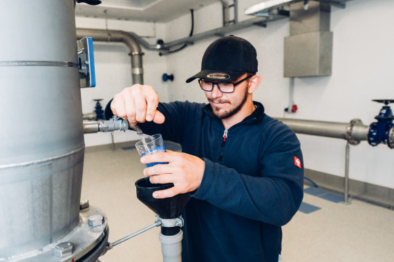 Ein Mitarbeiter des Wasserwerks entnimmt eine Wasserprobe aus einem Beh&auml;lter.