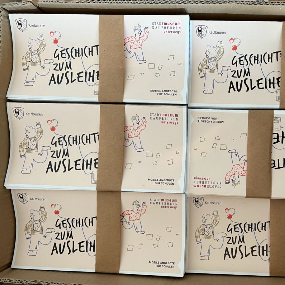 Foto eines Kartons mit gebündelten Faltblättern zu den unterwegs-Angeboten.