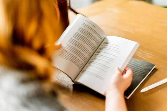 Frau seitlich fotografiert h&auml;lt ein Buch und liest